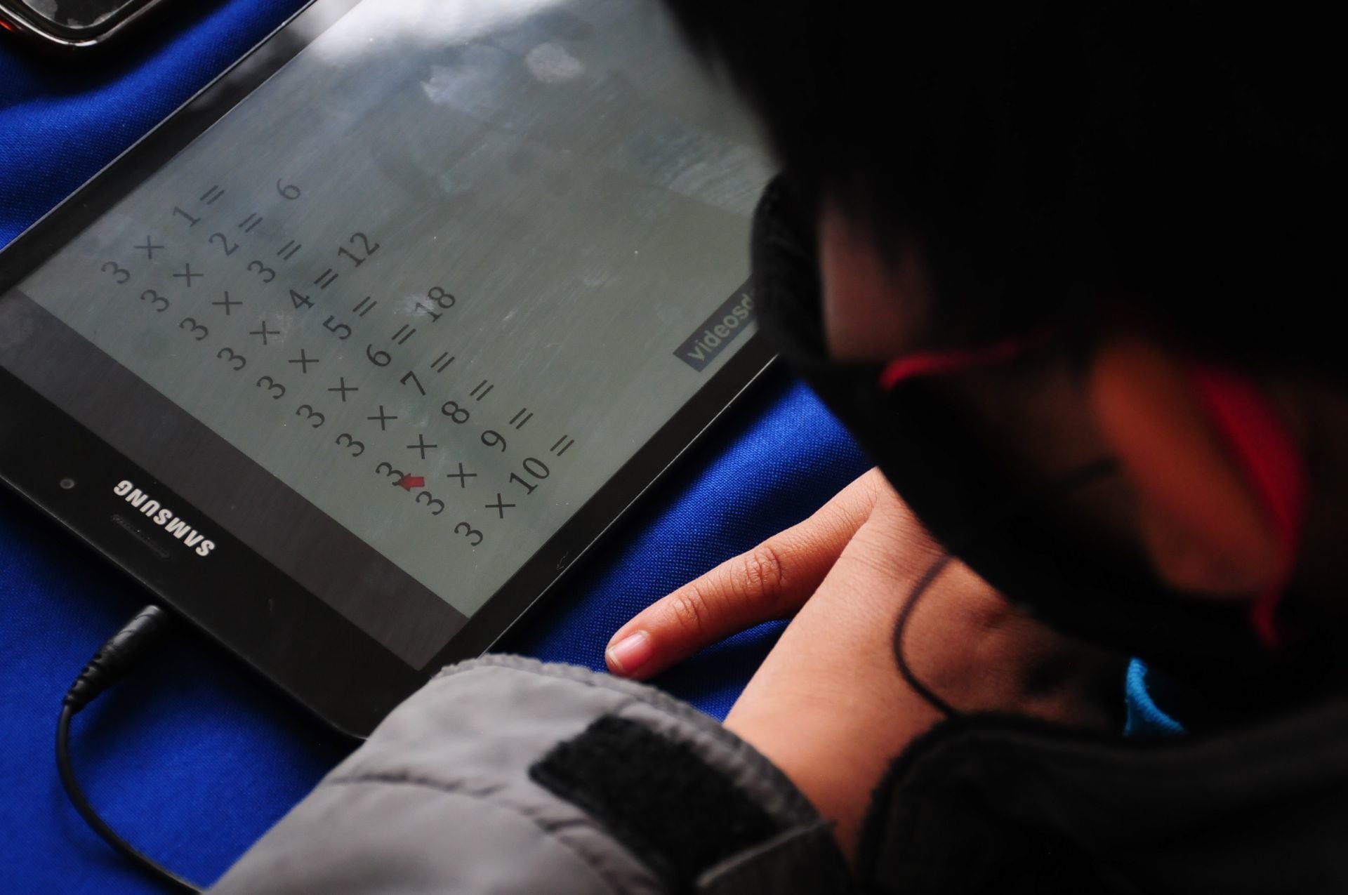 Un niño observa la tablet donde toma su clase de matemáticas